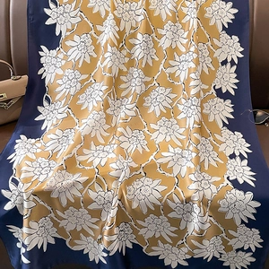Detailed view of floral silk scarf in navy and ginger yellow on premium leather