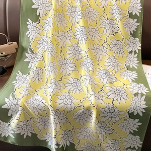Detailed texture of floral silk shawl with green borders on a leather sofa