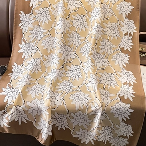 Detail of elegant floral silk scarf draped on leather background with fashion accessories