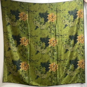 Detail of green floral silk shawl featuring yellow peony patterns and satin finish texture