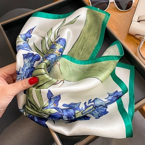 Élégant foulard en soie à imprimé iris avec bordure verte posé sur un plateau noir