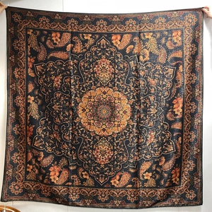 Detail of a large black shawl featuring orange floral paisley and mandala patterns