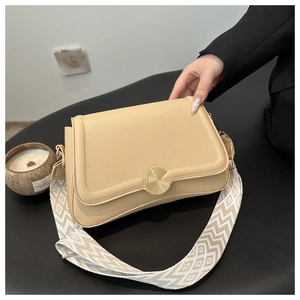 Detail of beige faux leather bag with lychee texture and gold-tone metal twist lock closure