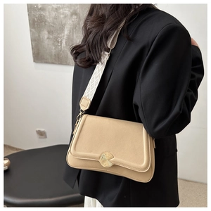 Detailed shot of beige lychee leather bag with geometric jacquard wide strap and gold buckle