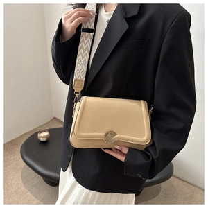 Detail of beige lychee leather bag featuring a gold disc buckle and wide jacquard strap