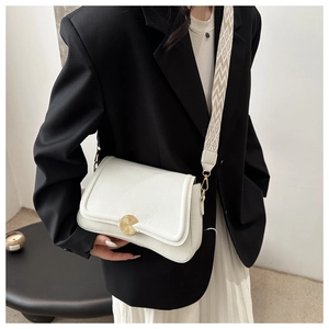 Close-up of white crossbody bag with gold round clasp and geometric wide strap