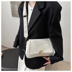 Detail of lychee textured leather crossbody bag with wide jacquard strap and gold lock