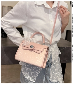 Detail of pink fashion handbag with white lace bow and silver metal twist lock