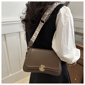 Detail of dark brown lychee leather bag with geometric pattern wide fabric strap