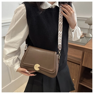 Detail of vintage brown leather bag with golden circular buckle and geometric strap