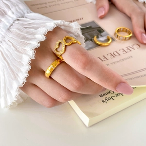 Detail of gold-plated heart ring with sparkling zircons worn with stacking bands