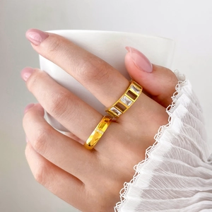 Macro detail of gold-plated rings with rectangular zircon stones and micro-pave diamonds