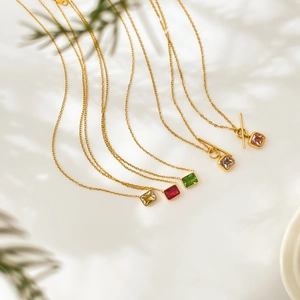 Détail de chaînes serpent dorées avec zircons carrés en émeraude, rubis et teintes violettes