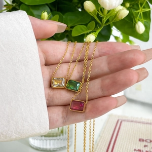 Détail de chaînes serpent dorées avec pendentifs rectangulaires en émeraude, rubis et zircon