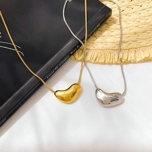 Colliers pendentifs haricot d'amour dorés et argentés avec chaîne serpent sur fond stylisé