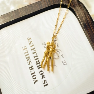 Detail of multi-layer gold embrace pendant necklace on a decorative art display card
