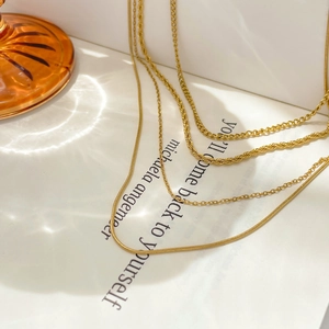 Detail of layered gold-plated necklaces with snake, twist, and Cuban chain textures