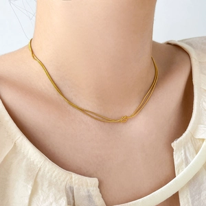 Detail view of 18K gold double-layer snake chain necklace with elegant love knot pendant