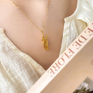 Close-up of 18K gold-plated hugging couple pendant on a delicate wavy necklace chain