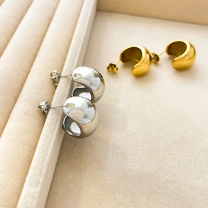 Polished 18K gold and silver dome stud earrings displayed on beige velvet jewelry tray