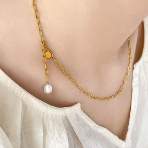 Detail of 18K gold snake chain necklace with baroque pearl charm and golden pendant tag