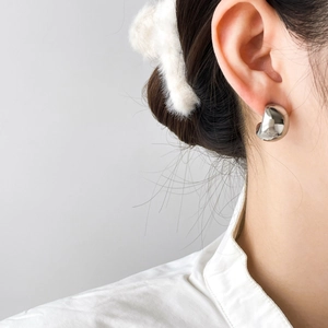 Macro detail of silver minimalist hollow dome hoop earring with mirror finish on model