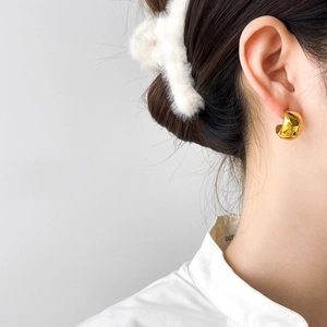 Polished 18K gold plated chunky C-shape hoop earrings worn by a model in a close-up side view