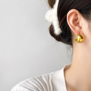 Close-up of 18K gold-plated C-shaped chunky earrings on a model showing smooth mirror finish
