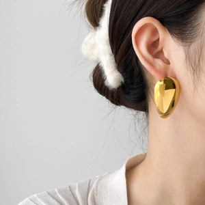 Side view of model wearing polished teardrop gold earrings with 18K gold finish