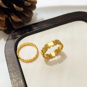 Détail de deux bagues en acier titane doré en forme de cœur sur un plateau à bijoux