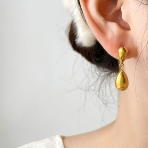 Close-up of elegant gold waterdrop earrings showing the layered metallic luster and fit