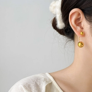 Minimalist gold-plated stainless steel double ball drop earrings on model's ear