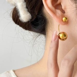 Close-up of elegant gold double sphere drop earrings worn on a model's ear