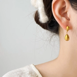 Detailed view of elegant double gold teardrop dangle earrings worn on a female ear
