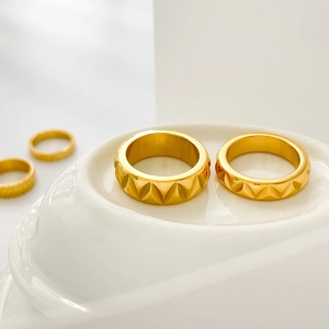Close-up of gold pyramid pattern rings with polished geometric textures on display