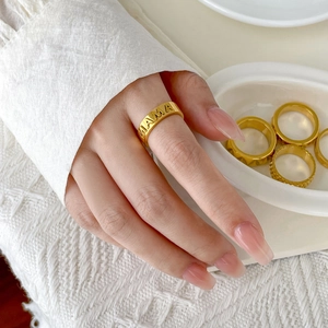 Close-up of gold plated stainless steel MAMA ring set on a knit background