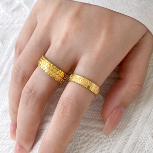 Close-up of gold titanium steel rings with honeycomb texture and sunray pattern details