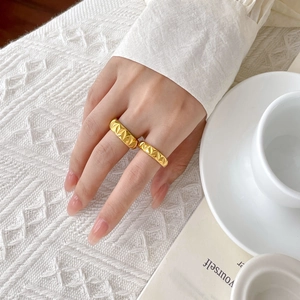Macro detail of 18K gold plated honeycomb and sunray pattern rings on a model hand