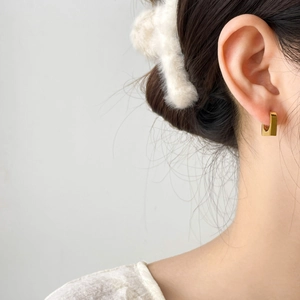 Orecchini geometrici quadrati dorati per donna mostrati indossati da una modella