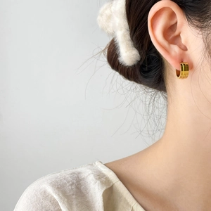 Orecchini a cerchio dorati a doppia fila indossati da una modella per un look trendy