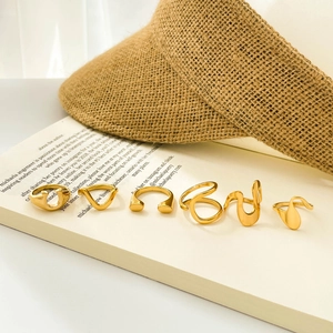 Five-piece set of minimalist 18K gold plated stainless steel wavy rings on a book