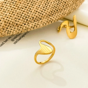 Detailed view of two irregular wavy 18K gold-plated rings with polished liquid surface finish