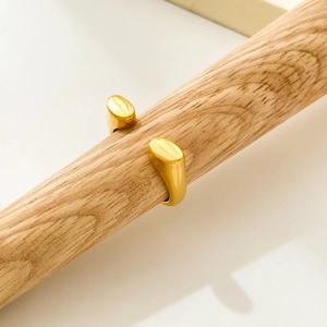 Detail view of double-ended oval design gold ring on a wooden display stand