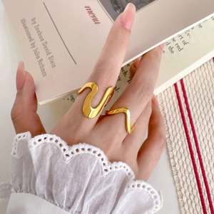 Detailed view of an irregular wavy gold ring with polished finish on a finger