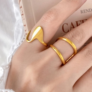 Close-up of gold geometric irregular rings on fingers with French book background
