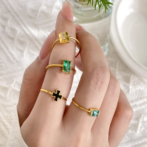Set of four 18K gold plated titanium rings with emerald, zircon, and black cross charms