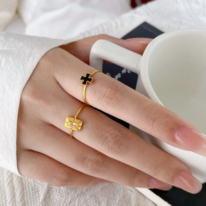 Detail of 18K gold rings with black cross and green zircon on a person holding a cup