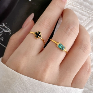 Close-up of gold titanium ring with green emerald cut zircon and black cross detail