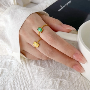 Detail of two adjustable 18K gold plated rings with green and clear zircon stones