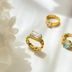 Detailed view of hollow gold-plated rings with rectangular and blue oval zircon stones